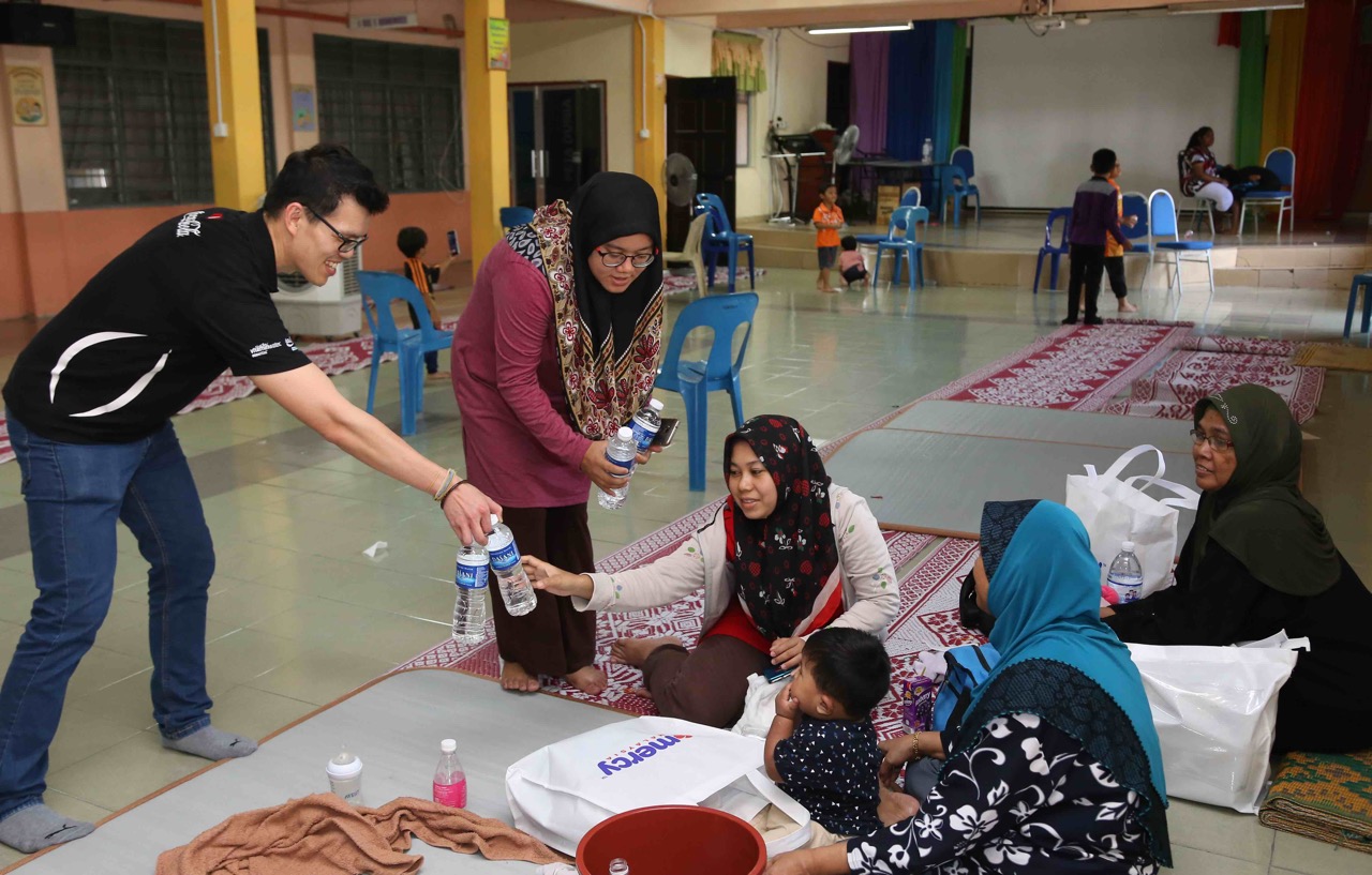 Para pekerja Coca-Cola mengagihkan air minuman Dasani kepada keluarga yang berlindung di SK Bertam Indah, Seberang Perai