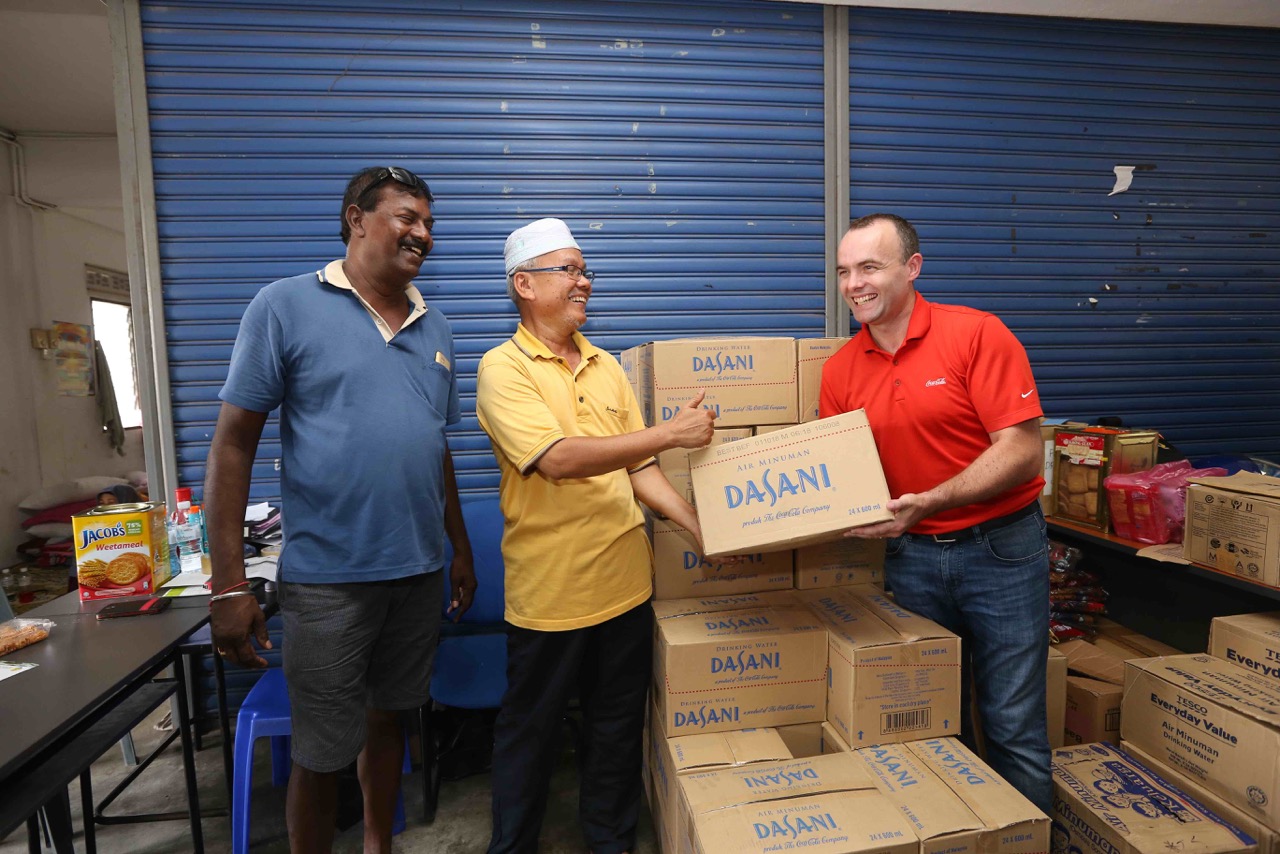 McGeown hands over drinking water to representatives from the Welfare Department at the Lubok Meriam relief centre